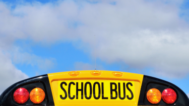 Back of a school bus with cloudy blue sky in background