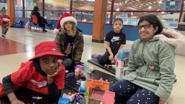 Four students playing with lego and sharing.