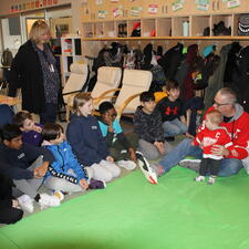 Group of students students sit and ask questions for the dad and baby visitors