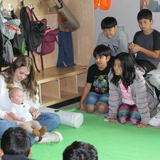 Group of students students sit and watch the mom and baby visitors