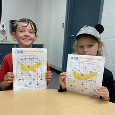 Two students holding papers