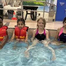 Four young kids sitting in the shallow end of the swimming pool